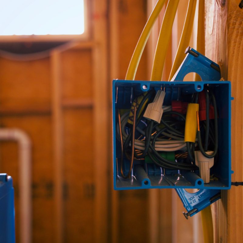 A blue box filled with electrical wires, arranged against a window