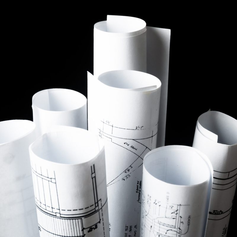 rolls of architecture blueprints and house plans on the black background