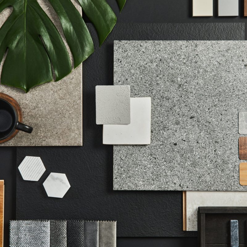 Flat lay composition of creative black architect moodboard with samples of building, textile and natural materials and personal accessories. Top view, black backgroung, template.